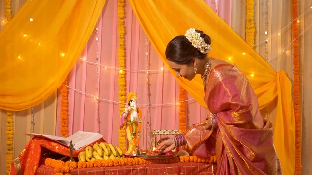 Indian woman wearing beautiful saree lighting diya for 'aarti ki thali' - Krishan Janmashtami . Indian stock video of a traditional and spiritual woman preparing thali for Krishna Puja at home - Fa...
