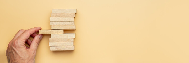 Male hand holding the middle wooden peg in a stack of them