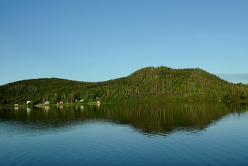 tree covered hill reflecting on a calm pond, Viking Trail Newfoundland Canada