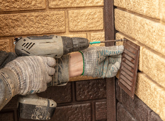 The worker sets the grille on the duct in the house