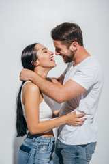 side view of young couple hugging while smiling and looking at each other