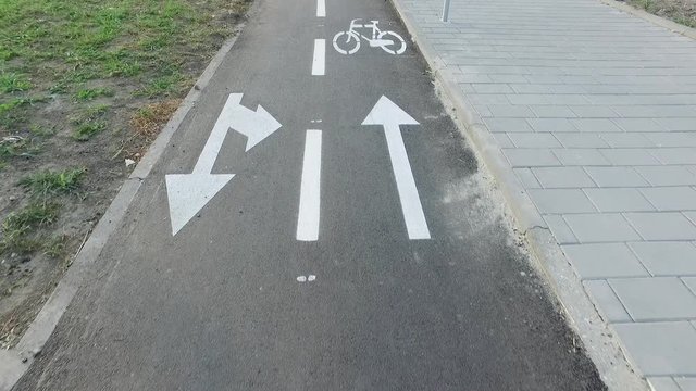 Bike lane, Bike lane with painted white bicycle sign or symbol and arrows on the ground for directions on new black tarmac road
