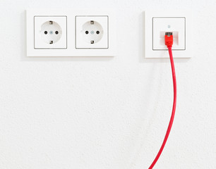Red network cable in wall outlet for office or private home lan ethernet connection with power...