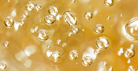 Bubbles of air on the smooth surface of golden water as an abstract background