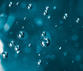 Bubbles of air on the smooth surface of blue water as an abstract background