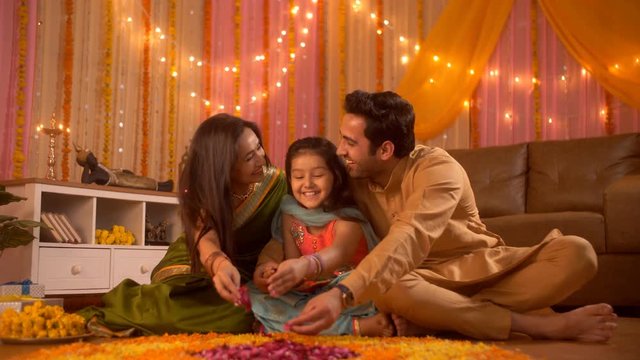 Diwali festival - An Indian nuclear happy family making Rangoli with flowers petal and loving their daughter. Indian stock video of a happy family celebrating Diwali festival in their new apartment