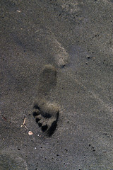 Footprint feet on the black sand, Tyrrhenian sea beach near Roma, Italy