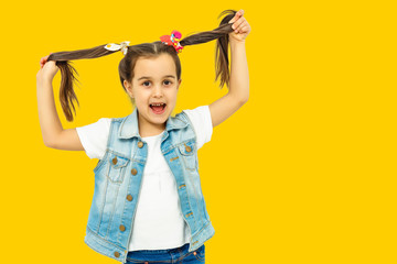 Happy five year old girl in bright joy over yellow background. Happy childhood. Copy space.