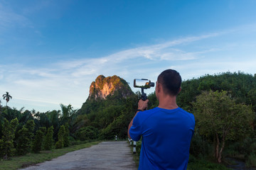 A vlogger is capturing a beautiful view by a gimbal and mobile phone.