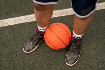 Ball by legs of young professional basketball player