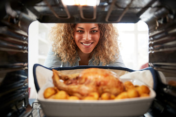 View Looking Out From Inside Oven As Woman Cooks Sunday Roast Chicken Dinner