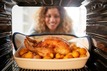 View Looking Out From Inside Oven As Woman Cooks Sunday Roast Chicken Dinner