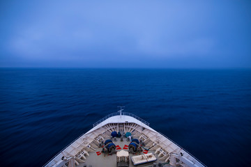View from the bridge of a ship traveling through fog, long exposure with motion blur on waves.