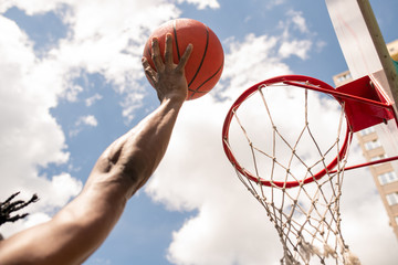 African basketball player throwing ball into basket during game or training
