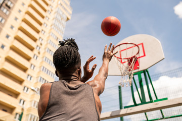 Fototapeta premium Rear view of young African basketball player throwing ball in basket