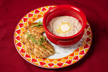 Bowl with prepared oatmeal with butter and chicken fillet
