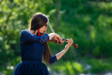 Young woman playing the violin at park. Shallow depth of field - image © ako-photography