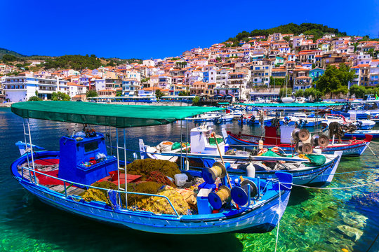Greece Lesvos Plomari town panorama, colorful houses on hillside from pier, high resolution of traditional fishing boats close up in Lesbos North Aegean Islands