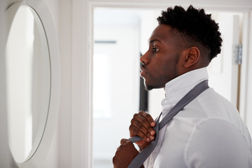 Businessman At Home Tying Necktie In Mirror Before Leaving For Work