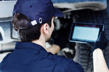 Mechanic is repairing car at service station. Repairman is conducting diagnostics and detecting...