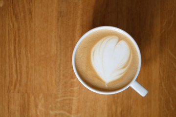 cappuccino in a white cup on a wooden table.