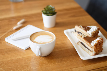 coffee in a Cup with a heart on a wooden table with a notebook and a tablet in a cafe with a flower work in the morning