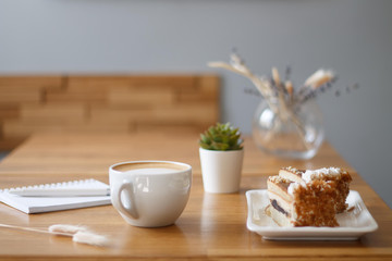 coffee in a Cup with a heart on a wooden table with a notebook and a tablet in a cafe with a flower work in the morning