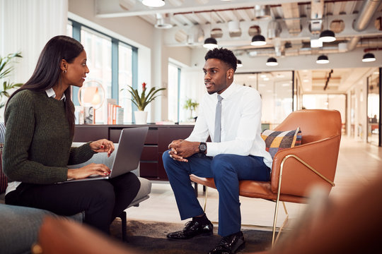 Businesswoman Interviewing Male Job Candidate In Seating Area Of Modern Office