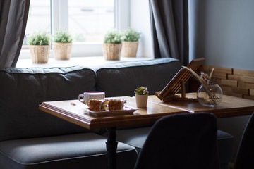 coffee in a Cup with a heart on a wooden table with a notebook and a tablet cake in a cafe with a flower work in the morning interior