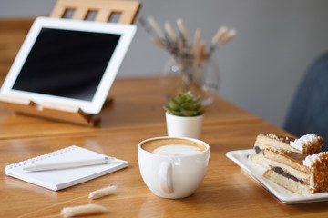 coffee in a Cup on a wooden table with a notebook and a tablet in the cafe work in the morning