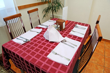 Table set at the dining room: spoons, forks on napkins 