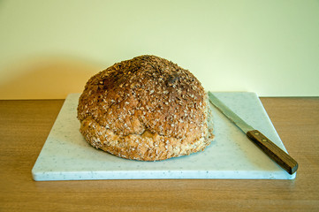 Loaf of bread and bread knife on a bread board.