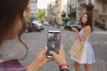 Cropped close up of a woman taking photos of her friend, using smart phone camera. Technology, social media, mobile app concept