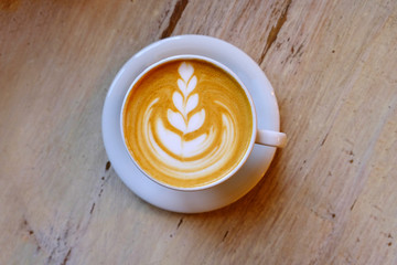 A cup of coffee cappuccino with latte art on wooden background. Coffee house