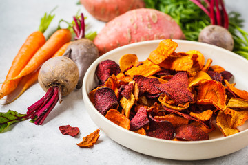 Bowl of healthy vegetable chips from beets, sweet potatoes and carrots on white background.