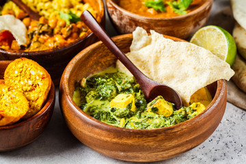 Traditional Indian palak paneer in wooden bowl on white background.