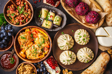 Traditional Georgian cuisine background. Khinkali, phali, chahokhbili, lobio, cheese, eggplant rolls, dark background. - obrazy, fototapety, plakaty