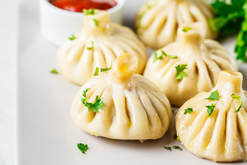 Georgian traditional dumplings khinkali with meat and greens on a white dish.