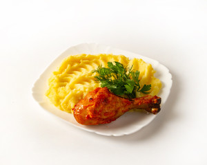 Portion of mashed potatoes with fried chicken leg and sprigs of greens on a plate © storyteller63
