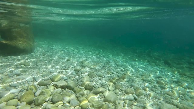 SLOWMO Underwater view of seabed with light being reflected on the various pebbles and rocks on the floor