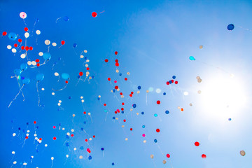 During the celebration of the holiday colorful balloons fly into the blue clear sky