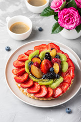 Tart with strawberries, kiwi, plums and cream