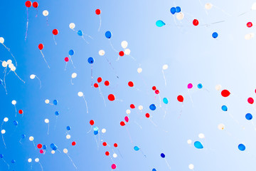 During the celebration of the holiday colorful balloons fly into the blue clear sky