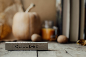 Wooden blocks against a rustic wood background with pumpkins and autumn leaves. Background with candle and pumpkin. Autumn background. Autumn months.