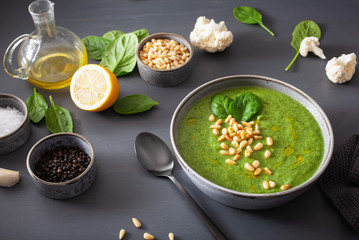 green creamy cauliflower spinach soup on gray background