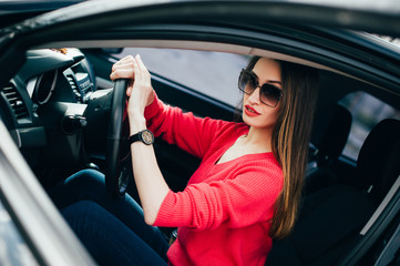 Fototapeta na wymiar Beautiful young business woman in sunglasses hurry up on meeting. She looking on watch on hand sitting in her black car. fashion girl in automobile ready to go! People Lifestyle Fashion Time concepts.