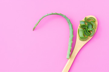 Medicinal plant aloe vera on a wooden spoon on a pink background
