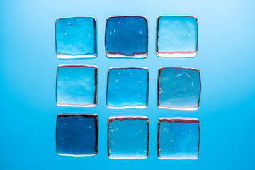Stylish blue background with transparent ice-like cubes for drinks. Flat lay macro photo.