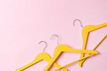 Creative flat lay yellow wooden hangers at pink background with copy space.