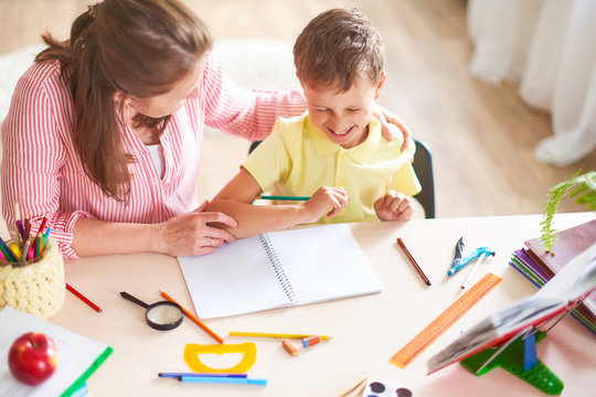 mother helps son to do lessons. home schooling, home lessons. the tutor is engaged with the child, teaches to write and count.